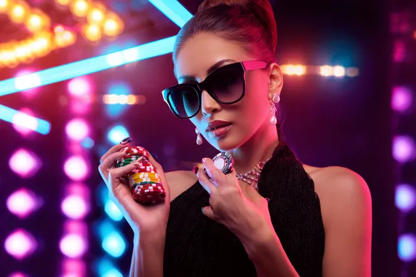 A young woman relaxing with her phone while dynamic casino elements float around her, illustrating the smooth mobile experience offered by the ZBZBED app.